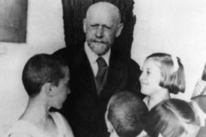 Janusz Korczak talking to a girl and boy student