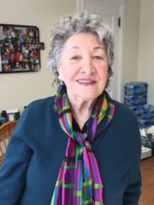 Ruth Mermelstein smiling while wearing a blue shirt and colorful scarf